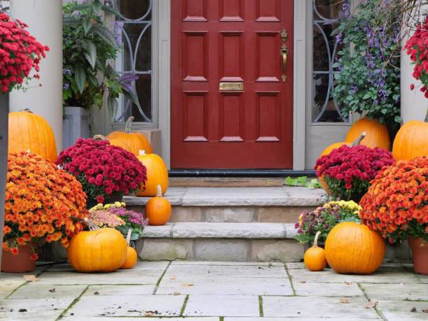 a front porch with pumpkins and a red door